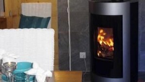 Une pièce chaleureuse avec un poêle à bois, une table à manger dressée et une lampe.