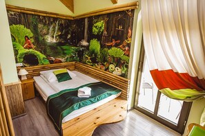 A room with a bed, a nightstand, a window with curtains, and a mural of a forest scene. - Pensjonat Kolory Świata (Solec-Zdroj)