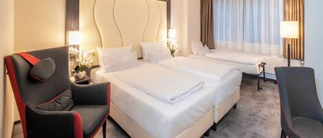 A hotel room with two beds, a sofa, a chair, and a large headboard.