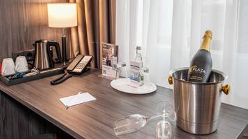 En hotelreception med en champagneflaske i en spand, en telefon, en notesblok og et glas.