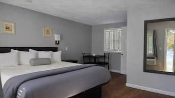 Un dormitorio con cama, mesita de noche, lámpara y ventana con persianas.