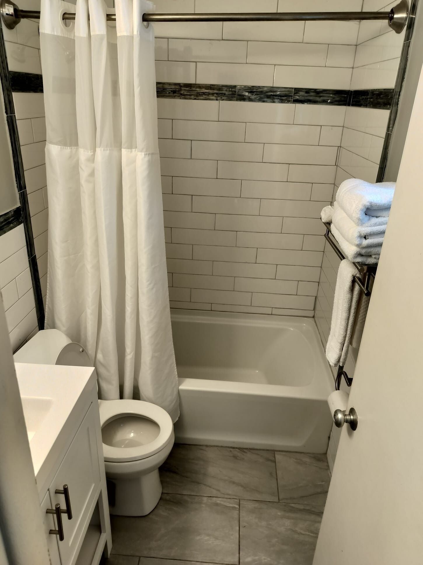 Un baño pequeño y funcional con inodoro blanco, bañera y cortina de ducha.