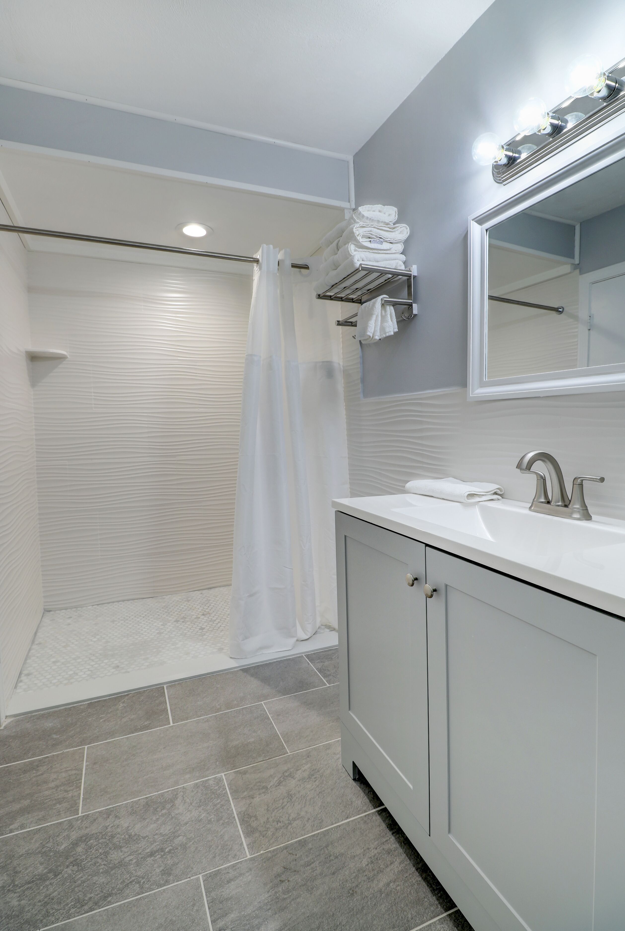 A modern bathroom with a shower, a sink, and a mirror.