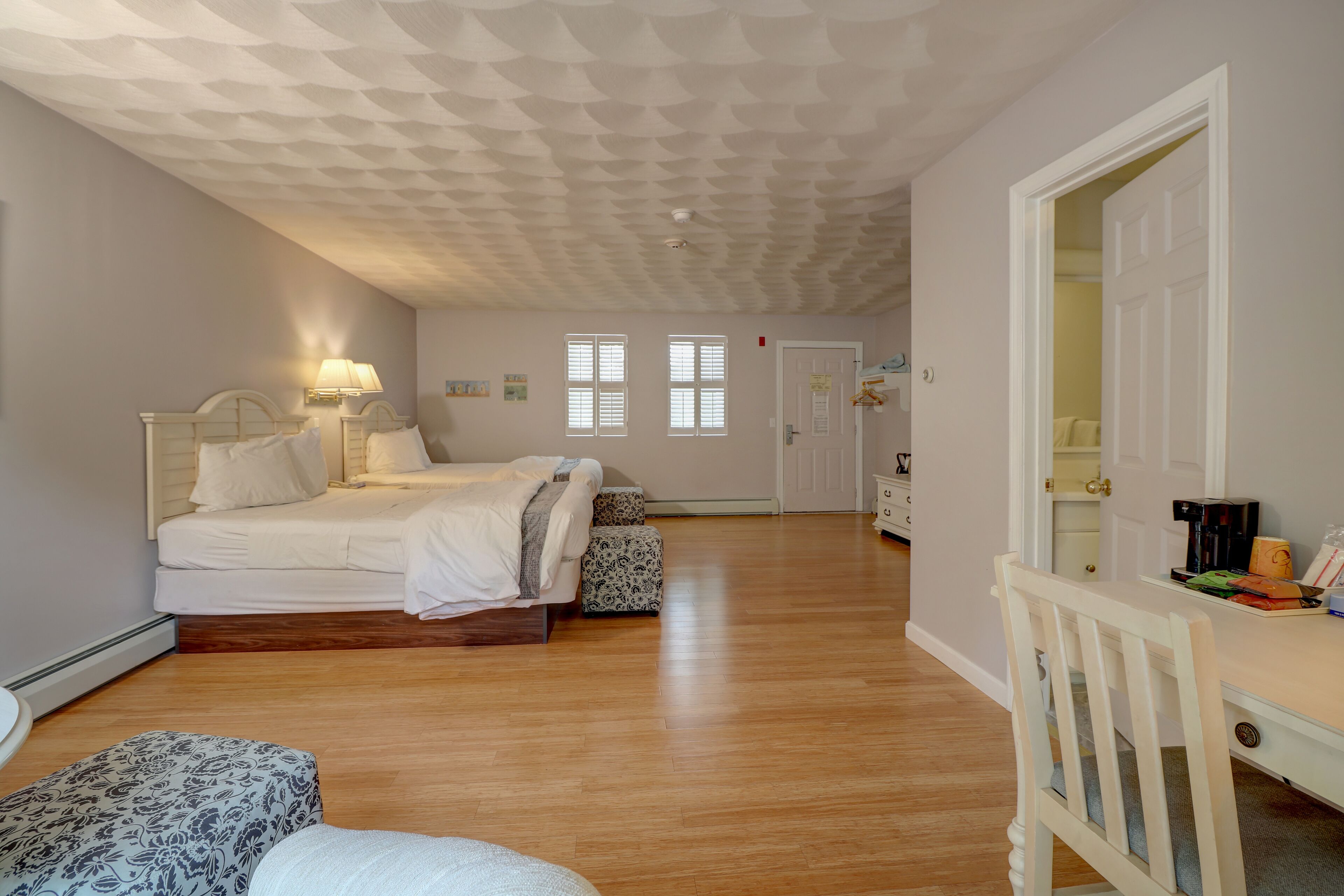 Un dormitorio con cama, mesita de noche, lámpara y escritorio con silla.