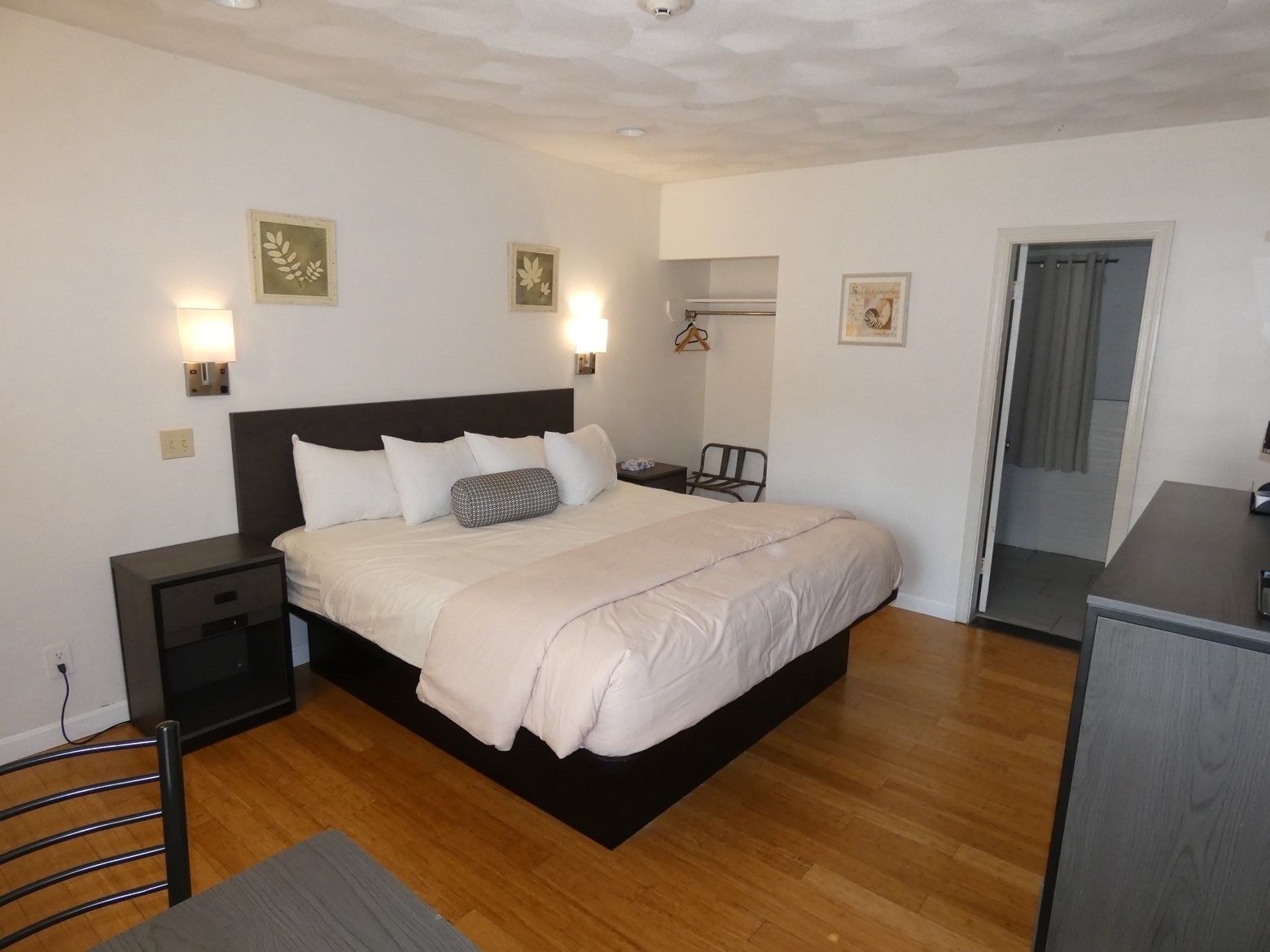 A hotel room with a bed, bedside tables, a desk, and a chair.