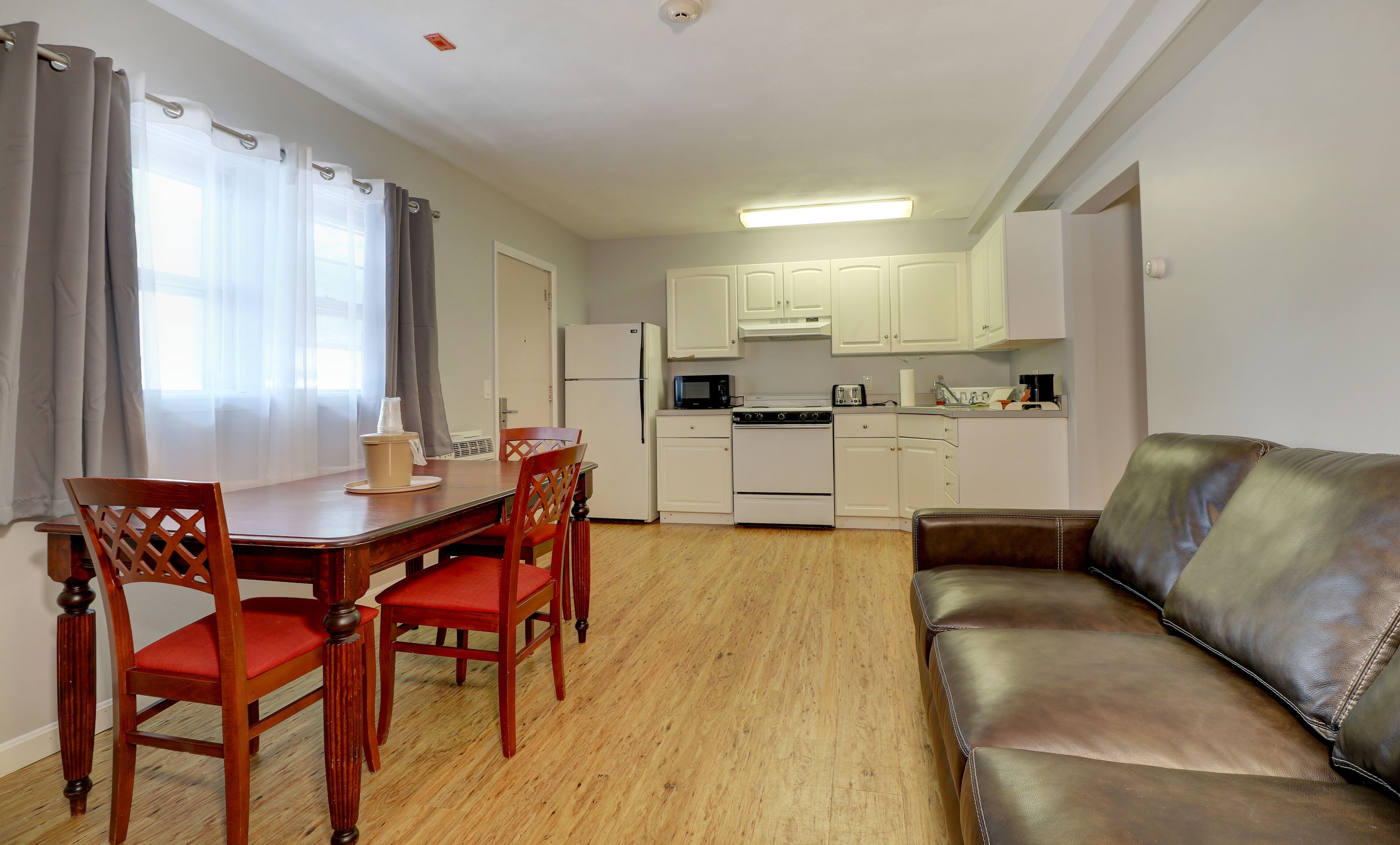 A compact living space with a dining area, kitchenette, and a leather sofa.