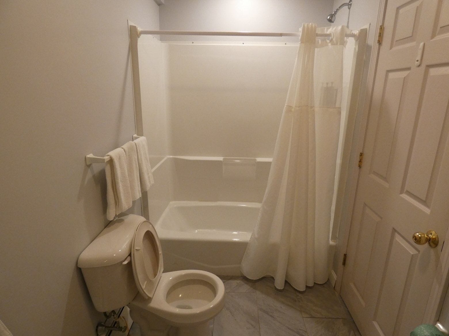 Een badkamer met toilet, bad en douchegordijn.