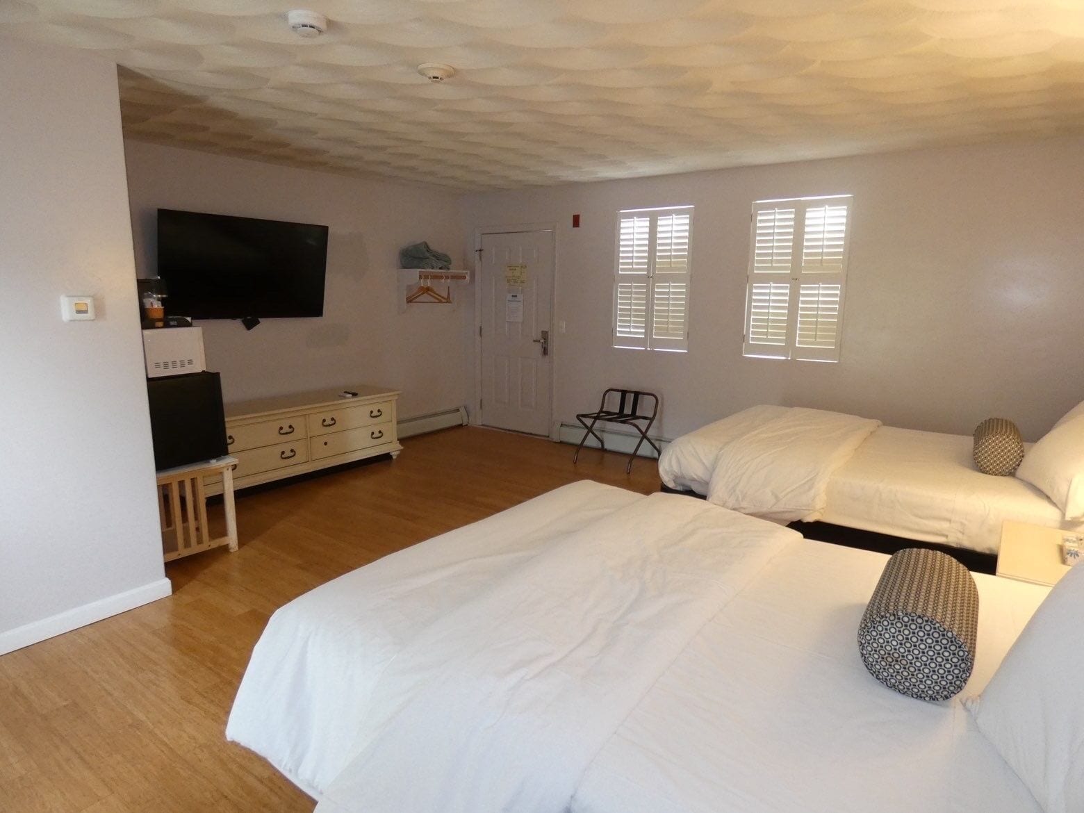 A bedroom with two beds, a TV, a dresser, and a chair.