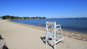 A beach with a lifeguard stand, a clear blue sky, and calm water. - Hamilton Village Inn (North Kingstown)