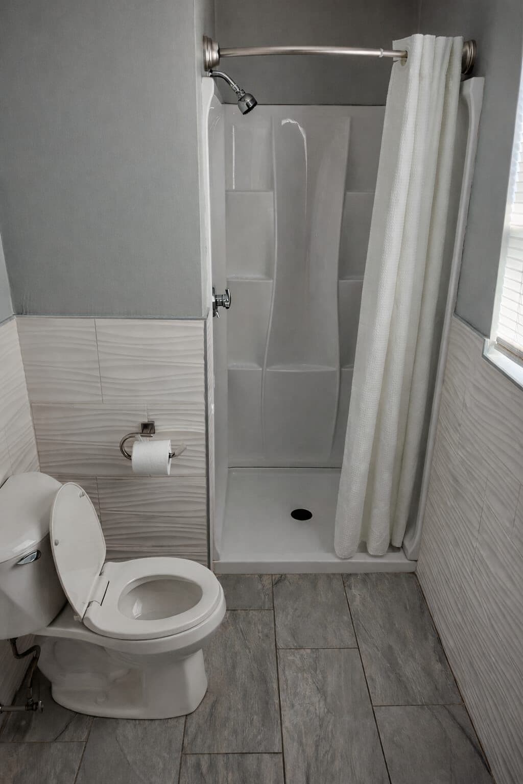 A bathroom with a toilet, shower, and a towel rack.