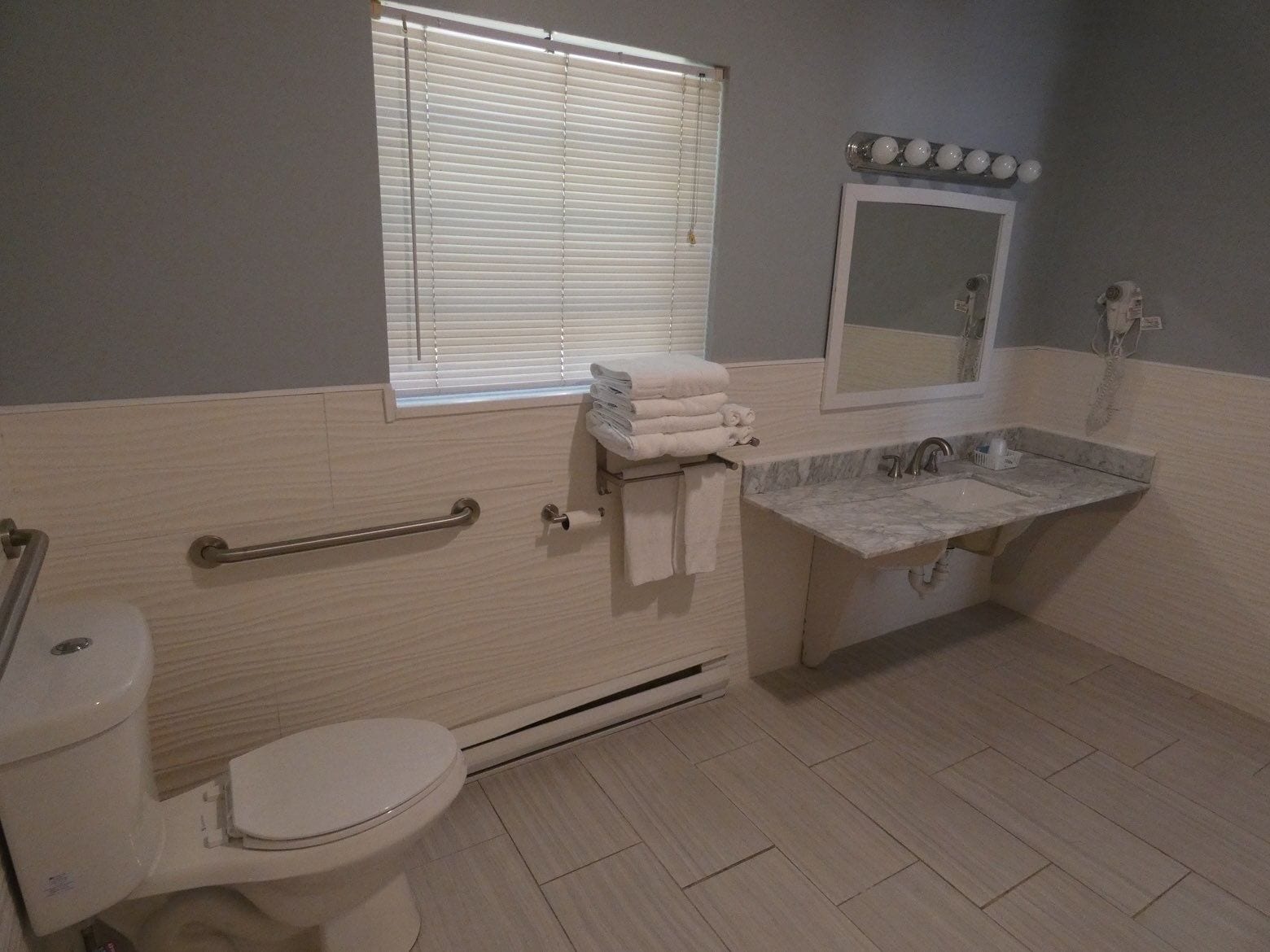 A bathroom with a toilet, sink, and window with blinds.
