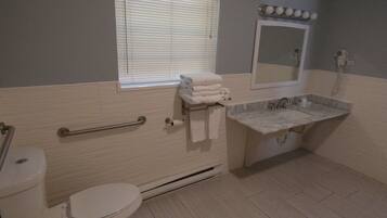 A bathroom with a toilet, sink, and window with blinds.