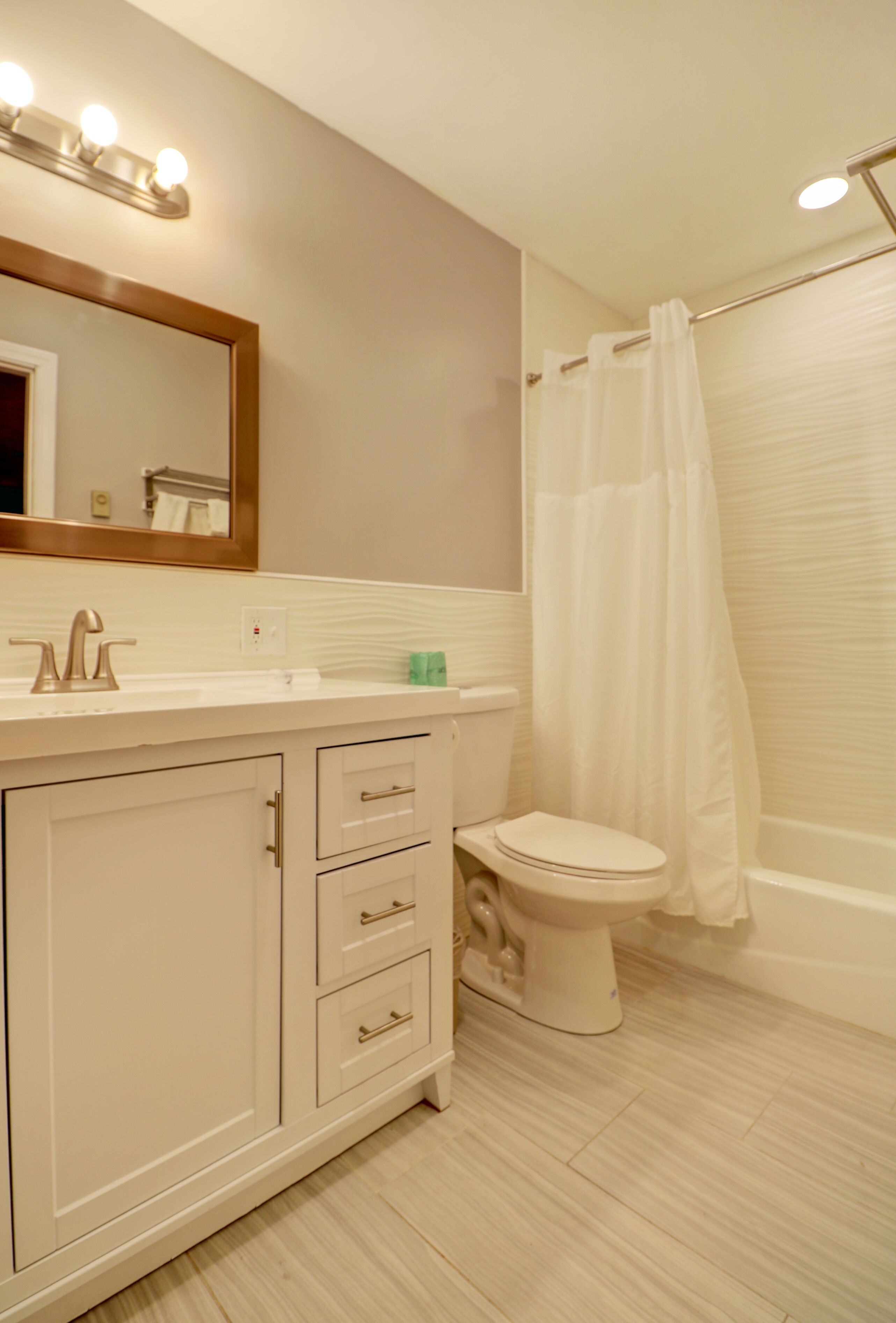 A bathroom with a white vanity, a toilet, and a shower curtain.
