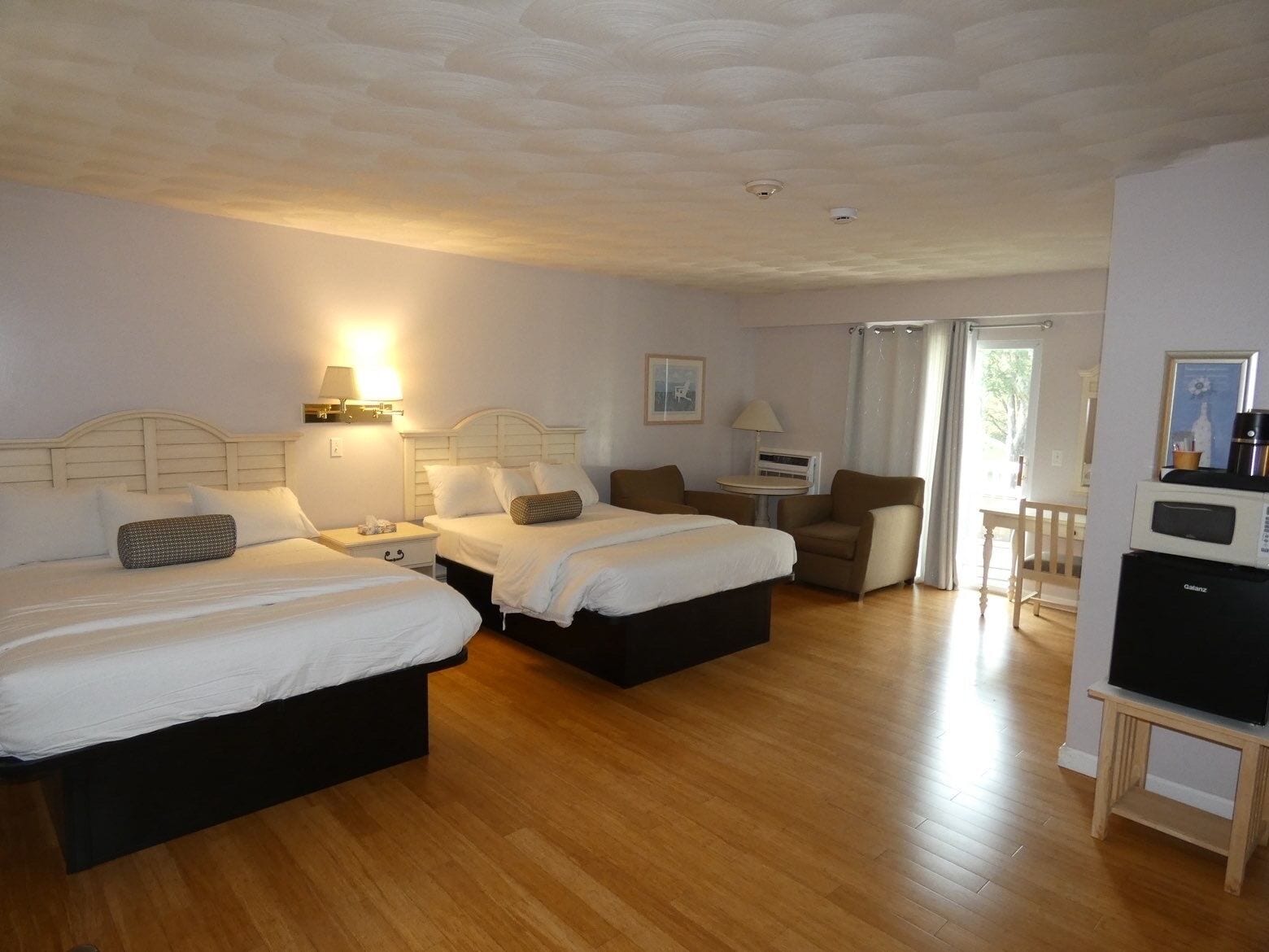 Habitación de hotel con dos camas, un escritorio, una silla y un televisor.