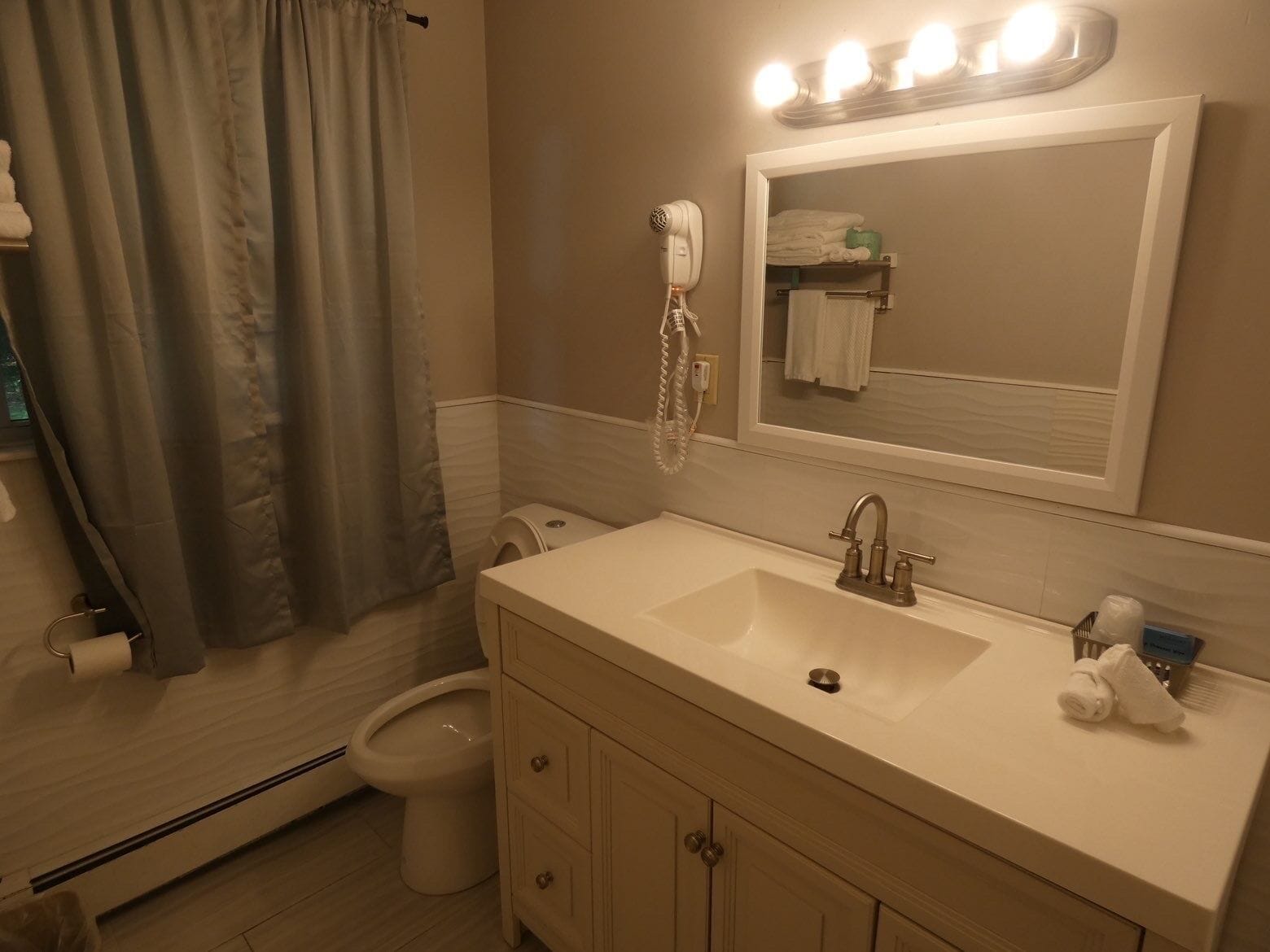 A bathroom with a sink, mirror, and a hairdryer.