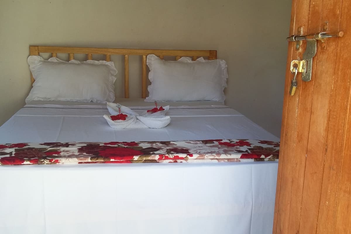 Un lit avec du linge de lit blanc, deux oreillers et une couvre-lit à motifs floraux.
