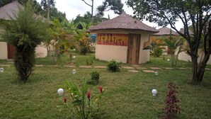 A garden area with thatched-roof huts, surrounded by greenery and small decorative spheres.