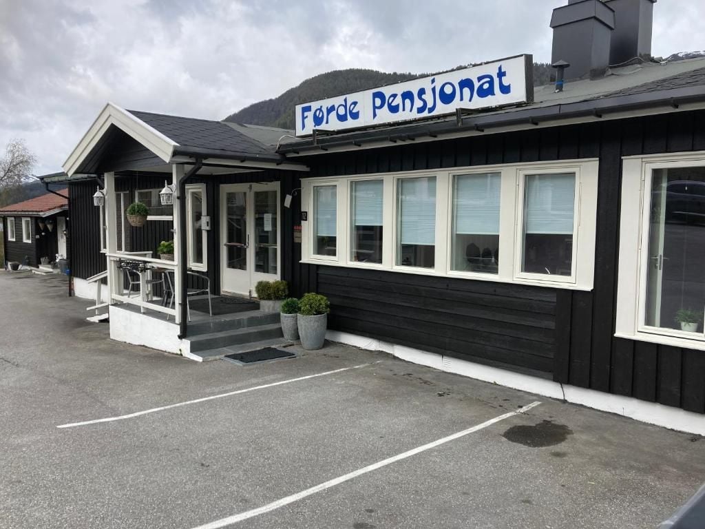 Ein Gebäude mit einem Schild, auf dem 'Forde Pensionat' steht, und einem überdachten Eingang mit Stufen zu einer Tür.