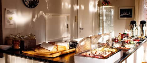 A buffet area with various food items, a clock, and a glass cabinet with glasses.
