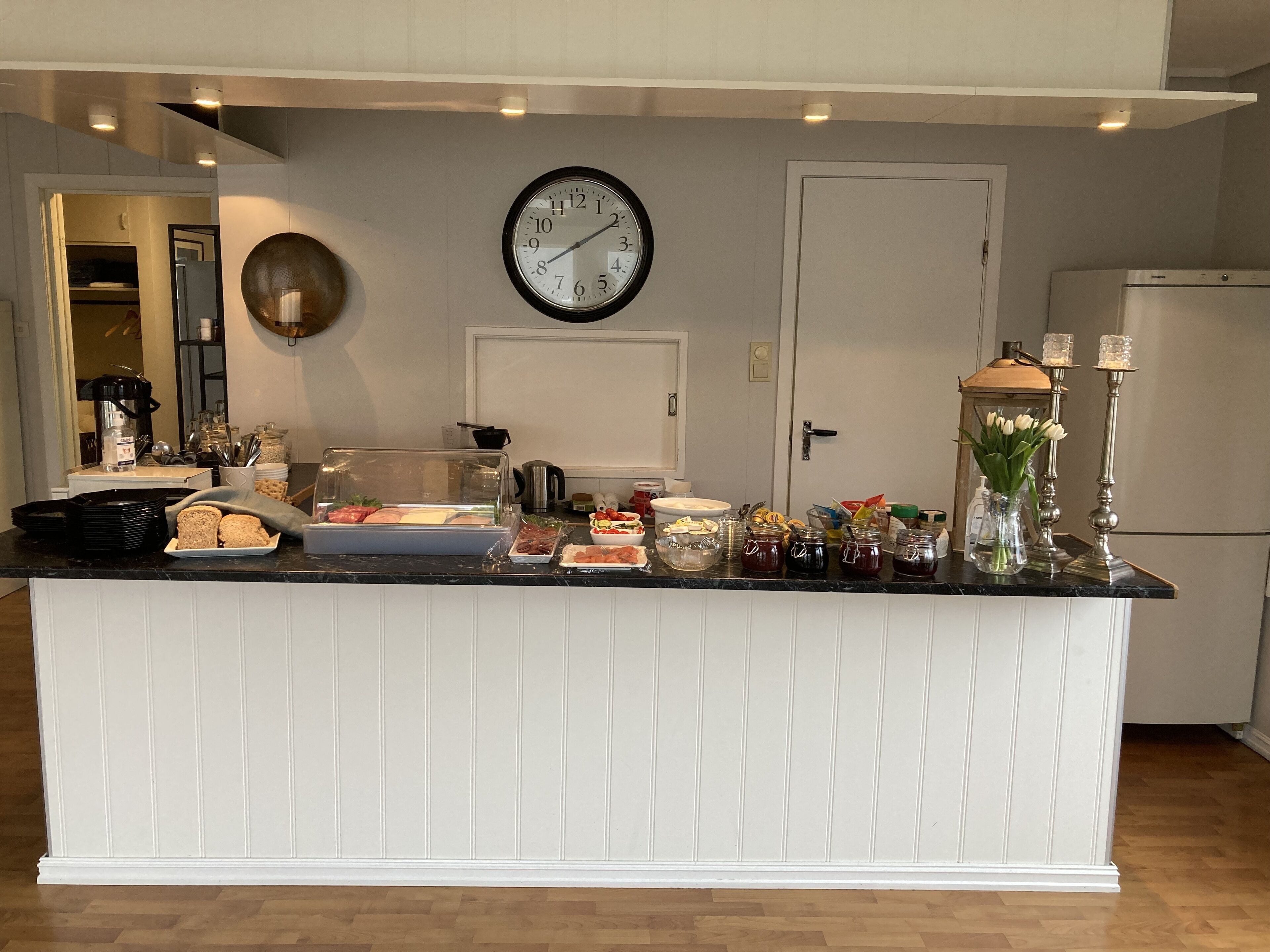 A kitchen with a breakfast bar, a clock, and various food items.