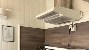 Una kitchenette compacta con microondas, horno y nevera pequeña.