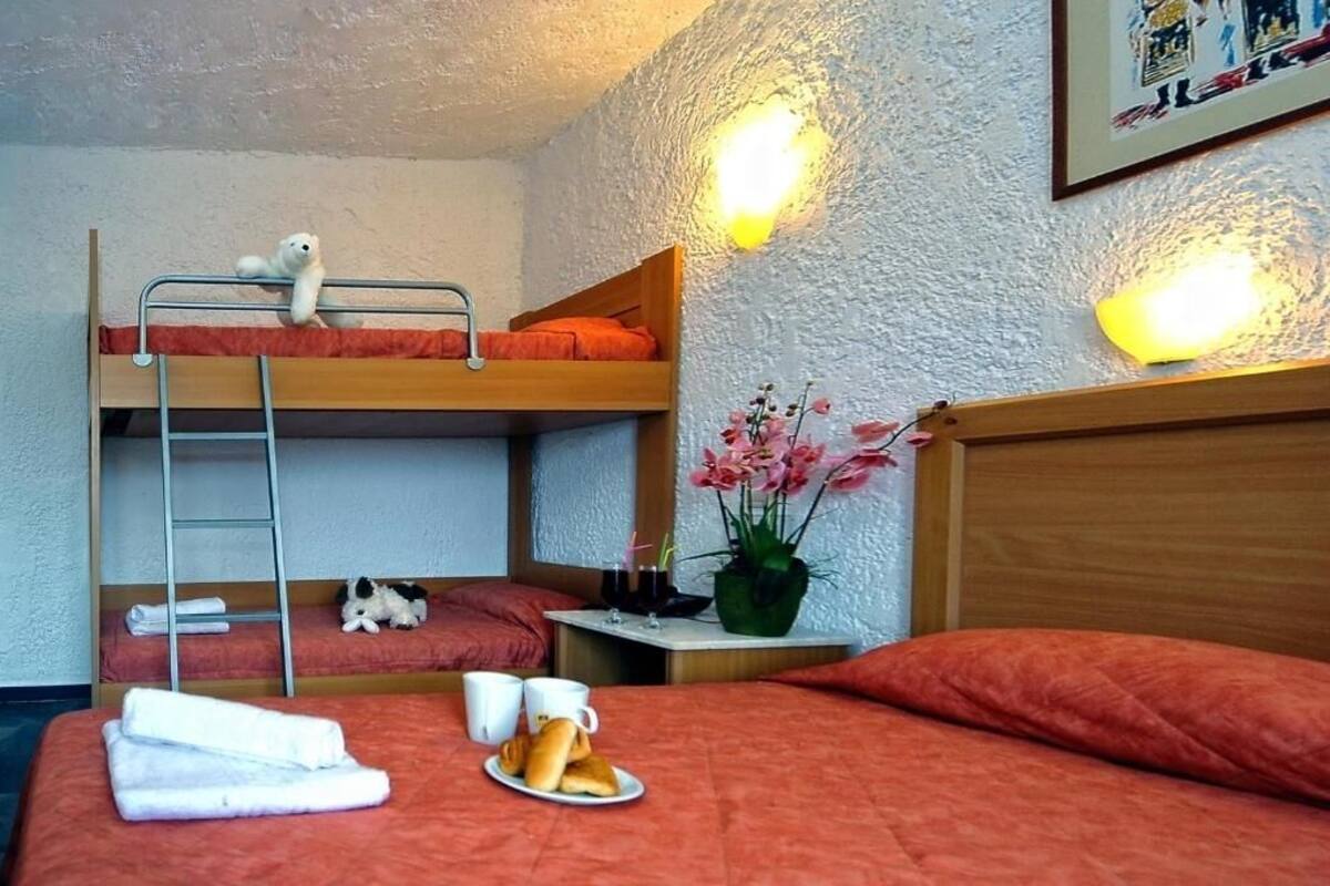 Una habitació de dormitori amb lliteres, una taula petita amb un vas de flors i un safata de matí a la llitera inferior.