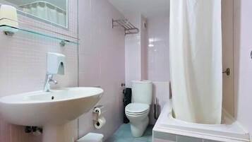 Un baño con lavamanos, inodoro y zona de ducha.