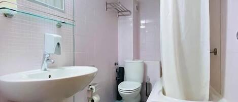 Un baño con lavamanos, inodoro y zona de ducha.