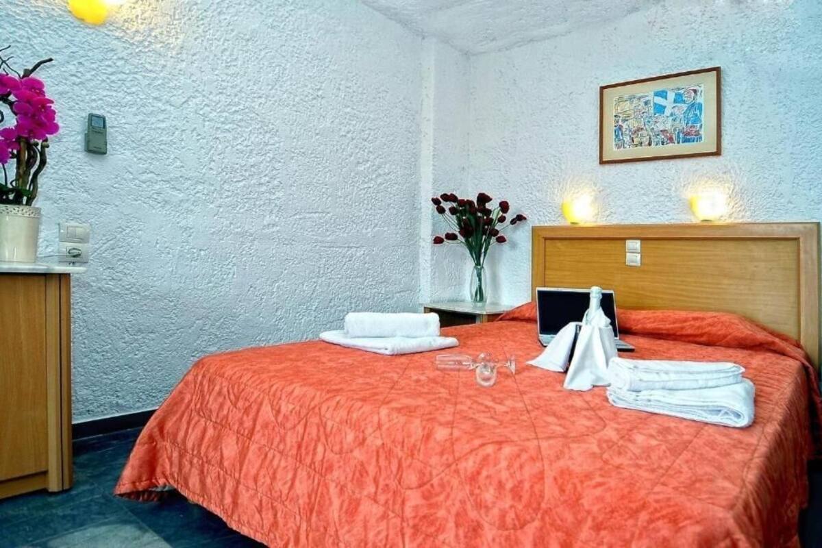 Habitació d'hotel amb un llit, una taula de nit amb un ram de flors, un quadre al mur i una tauleta de nit amb una làmpada.