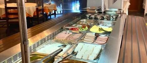 A buffet with various food items, including meats, cheeses, and fruits.