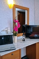 Una habitación con un armario de madera, una computadora portátil, una botella de vino, una copa y un florero con flores rosadas.