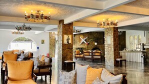 Een ruime lobby met een hoog plafond, weelderige kroonluchters en een stenen openhaard.