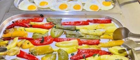 Een buffet met diverse gerechten, waaronder eieren, groenten en worstjes.