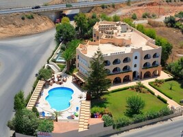Un hotel con piscina, mobiliario exterior y un jardín ajardinado.