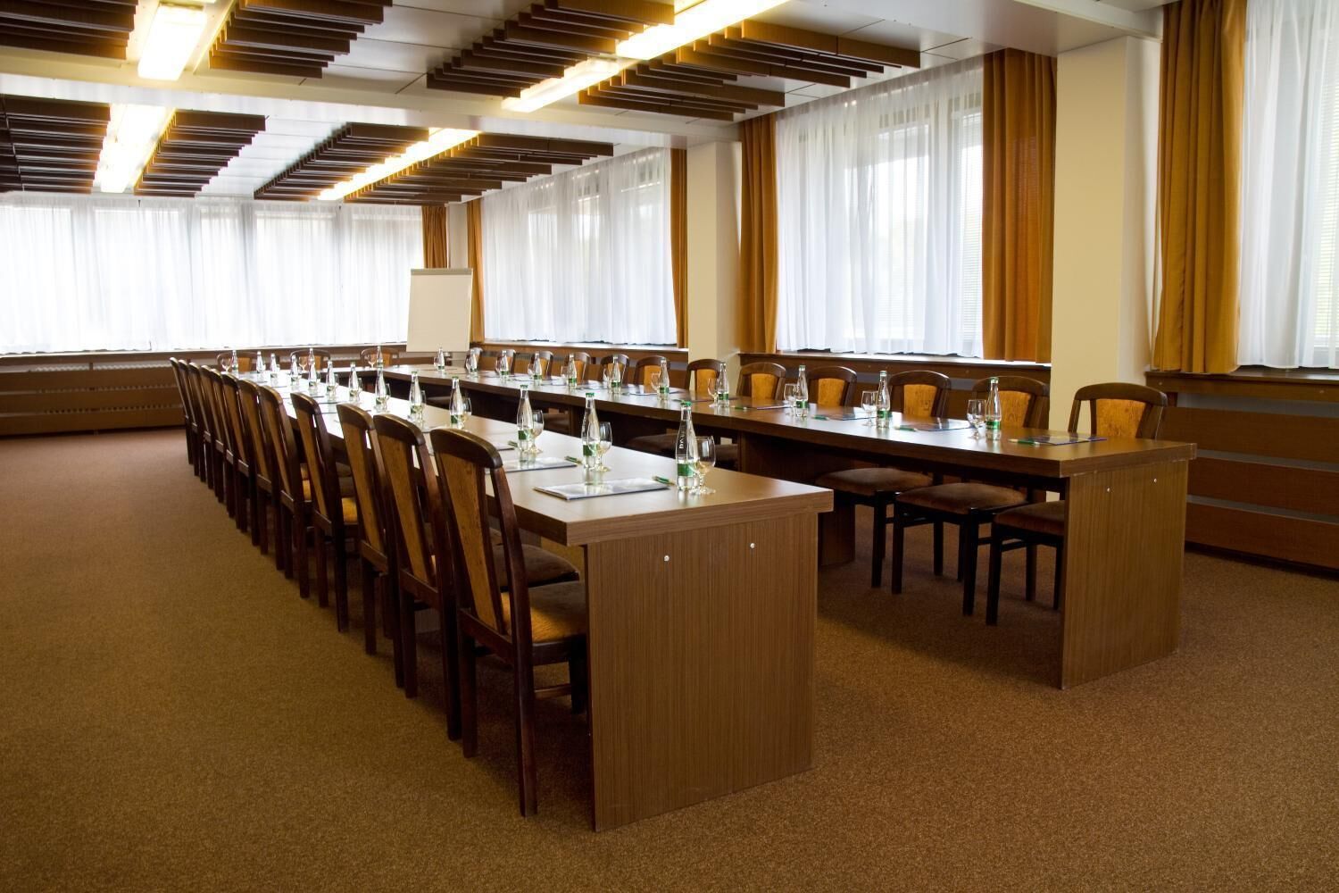 Ein Konferenzraum mit langen Tischen, Stühlen und einem Rednerpult.