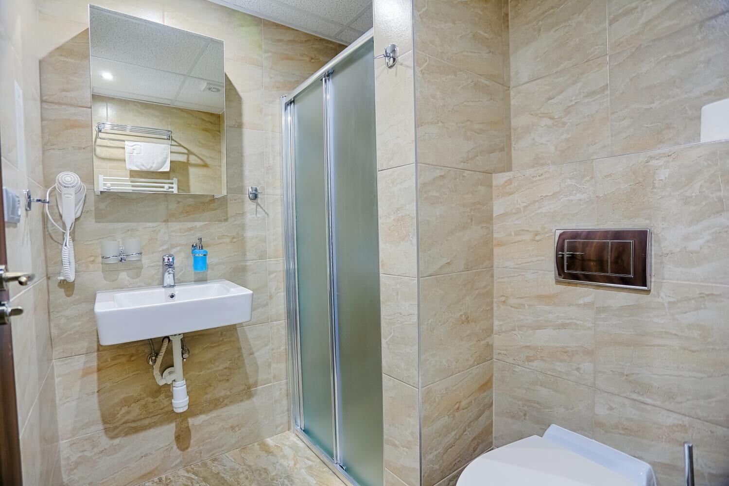 A modern bathroom with a glass shower enclosure, a white sink, and a towel rack.