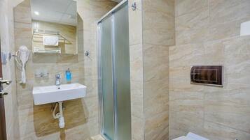 A modern bathroom with a glass shower enclosure, a white sink, and a towel rack.