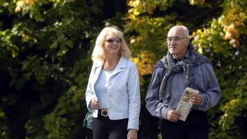 Two people walking on a path in a park with trees in the background.