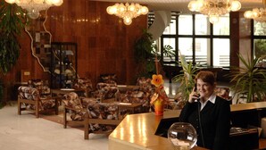 A reception area with a receptionist, wooden furniture, and large windows. - Ensana Spa Smrdaky (Smrdáky)
