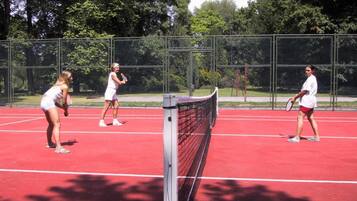 Ein Tennisplatz mit Netz in der Mitte, umgeben von einem Maschendrahtzaun.