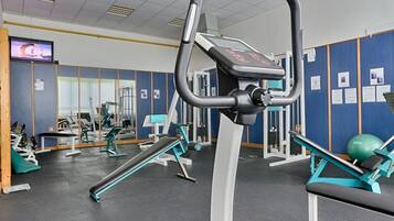 A gym with exercise equipment, a television, and a mirror.