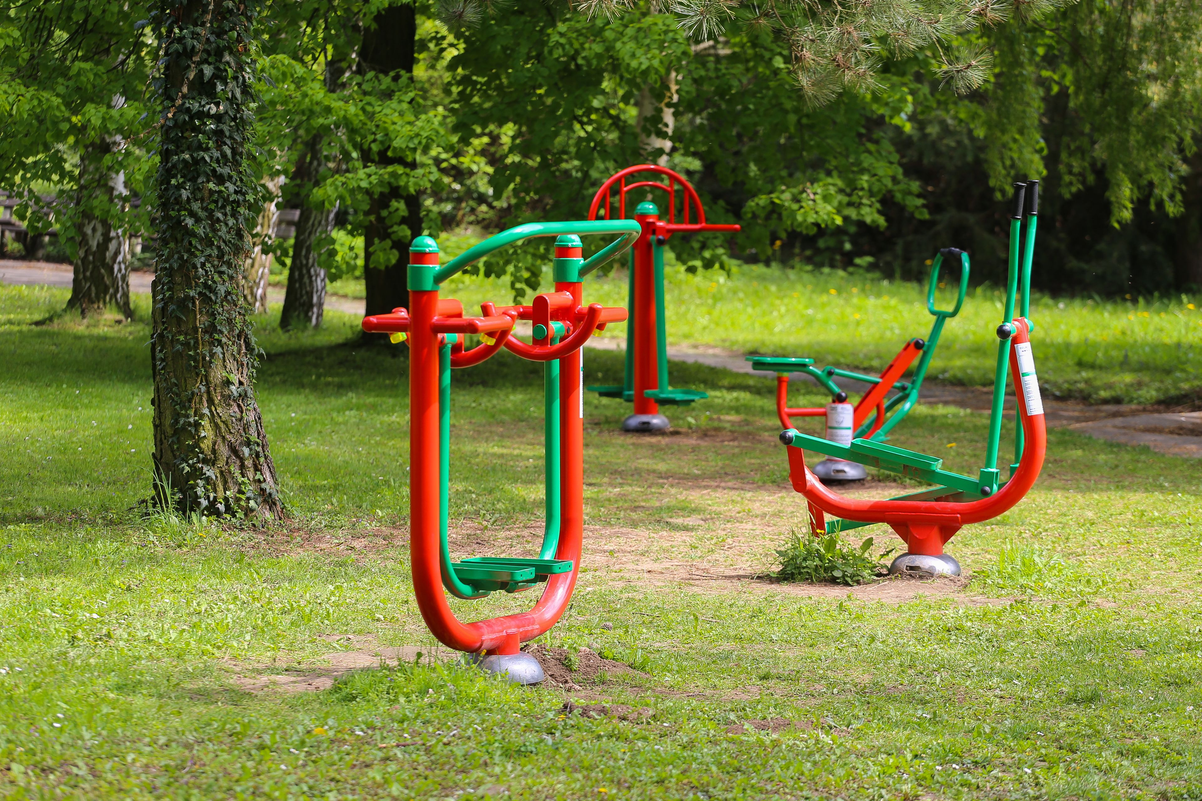 Outdoor exercise equipment in a park with green grass and trees.