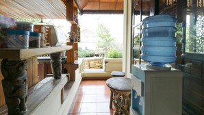 Un couloir étroit doté d’un sol carrelé, d’un banc en bois, d’un distributeur d’eau et d’une table sur laquelle se trouvent des récipients.