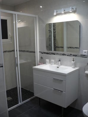 A bathroom with a white vanity, a glass shower enclosure, and a mirror above the sink.