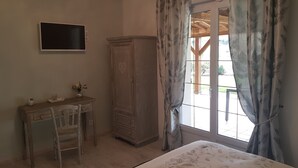 Une chambre à coucher comprenant un lit, une armoire en bois, un bureau avec une chaise et un téléviseur fixé au mur.
