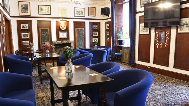 A room with blue upholstered chairs, a wooden table, and a patterned carpet. - Dinorben Arms Hotel (Amlwch)