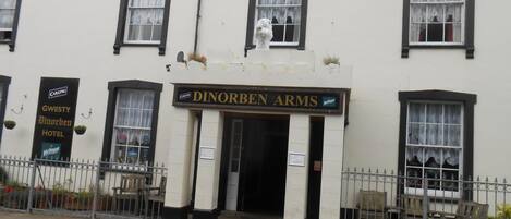 Un edificio con un cartel que dice "Dinorben Arms" y otro cartel para "Gwesty Dinorben Hotel".