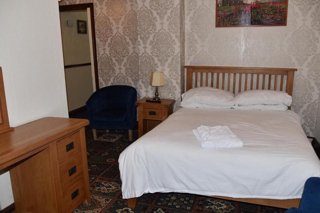 Habitación de hotel con cama, escritorio, silla, mesita de noche con lámpara y pared con diseño.