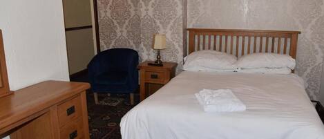 Habitación de hotel con cama, escritorio, silla, mesita de noche con lámpara y pared con diseño.