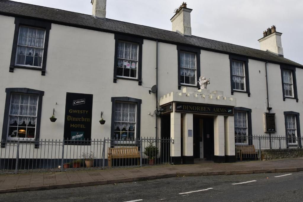 A building with a sign for 'Gwesty Dinorben Hotel' and 'Dinorben Arms' on the facade.